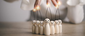 La main d'une femme manipule des individus représentés par des personnages en bois - MACSF