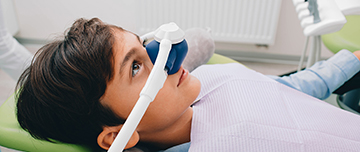 Jeune garçon, sur le fauteuil du dentiste, portant un masque pour l'administration de meopa - MACSF