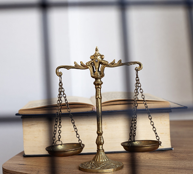 Un code pénal et la balance de la justice posés sur un bureau - MACSF