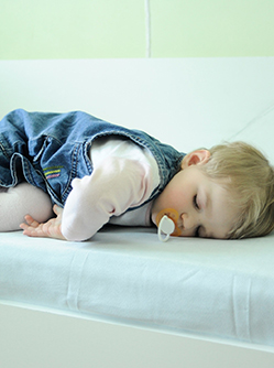 Une petite fille dort sur le bord d'un lit - MACSF