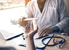Un médecin tend un document au patient - MACSF