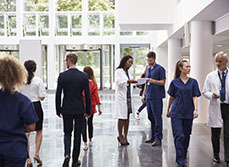 Médecins et patients se déplacent dans un hall d'hôpital - MACSF