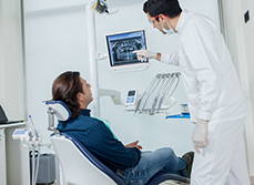 Le dentiste pointe une radio dentaire en expliquant les soins au patient - MACSF