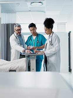 Trois soignants examine le dossier d'un patient dans la chambre de l'hôpital - MACSF