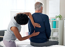 Une femme médecin examine le dos d'un patient - MACSF