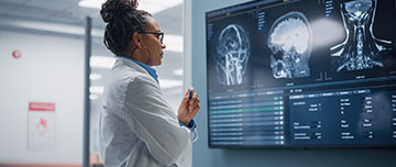 Une radiologue étudie des clichés radiologiques affichés à l'écran - MACSF