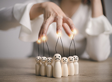 La main d'une femme manipule des individus représentés par des personnages en bois - MACSF