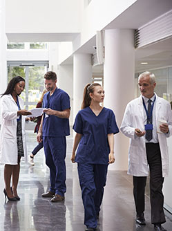 Médecins et patients se déplacent dans un hall d'hôpital - MACSF