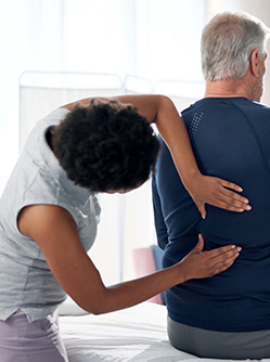 Une femme médecin examine le dos d'un patient - MACSF