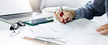 Main d'homme signant un document sur le bureau - MACSF