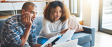 Un couple avec des documents devant leur ordinateur - MACSF