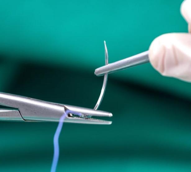 Mains d'infirmier tenant une pince et une aiguille de suture - MACSF