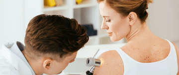 dermatologue analysant un grain de beauté