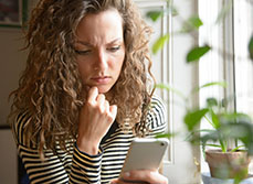 Femme étonnée regarde son téléphone portable - MACSF