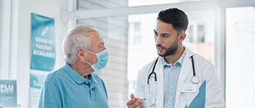 Un médecin discute avec un patient âgé et tient un dossier dans sa main - MACSF