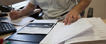 Un homme à son bureau examine des documents - MACSF