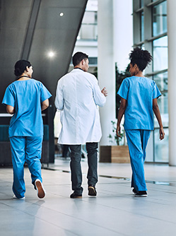 Trois professionnels de santé marchent dans le hall d'un hôpital - MACSF