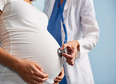 Une sage-femme applique le stéthoscope sur la ventre d'une femme enceinte - MACSF