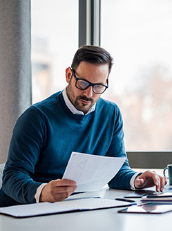 Un homme assis à son bureau lit un document - MACSF