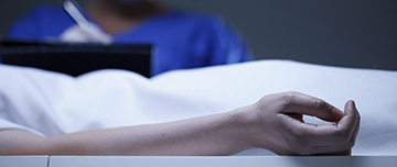 Gros plan sur le bras d'une défunte. Buste du médecin en second plan - MACSF
