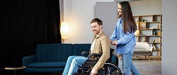 La jeune femme pousse un jeune homme en fauteuil roulant - MACSF