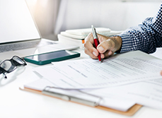Main d'homme signant un document sur le bureau - MACSF