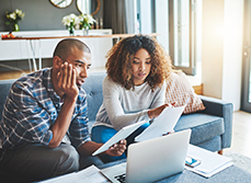 Un couple avec des documents devant leur ordinateur - MACSF