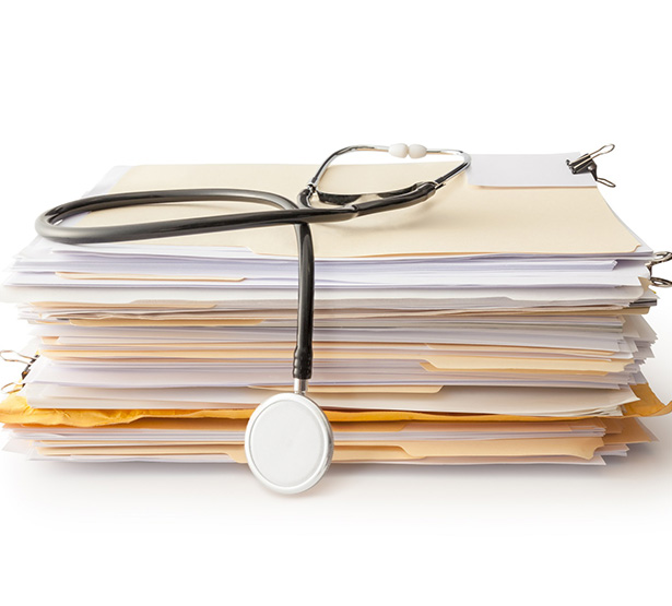 Un stéthoscope posé sur une pile de dossiers médicaux - MACSF