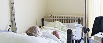 Une femme âgée alitée dans un lit d'hôpital - MACSF