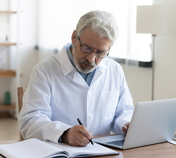 Un médecin à son bureau écrivant sur un cahier - MACSF
