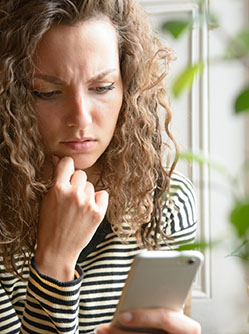 Femme étonnée regarde son téléphone portable - MACSF