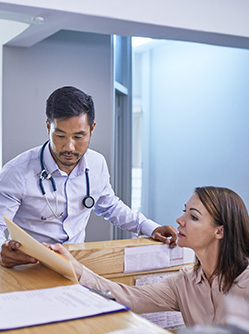 Médecin et réceptionniste discutant du dossier médical – MACSF