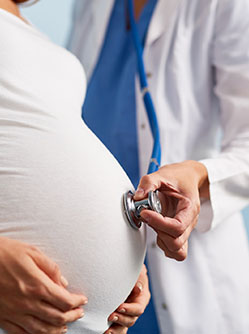 Une sage-femme applique le stéthoscope sur la ventre d'une femme enceinte - MACSF