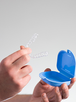 Main d'un homme tenant une gouttière orthodontique - MACSF