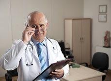 Un médecin senior souriant tient en main un dossier - MACSF