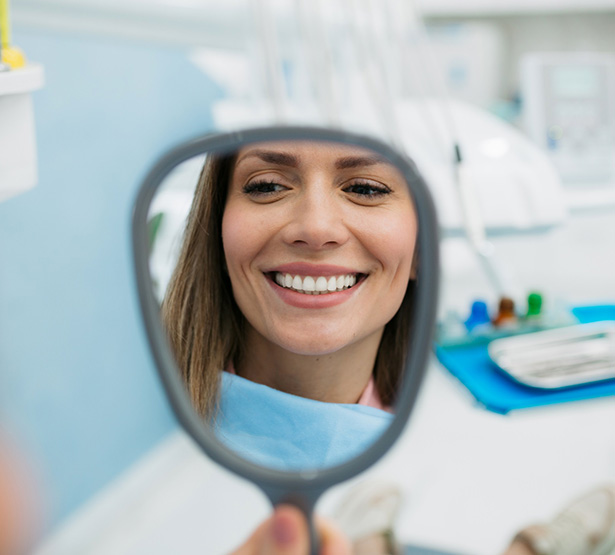 Une jeune femme souriante devant le miroir chez le dentiste - MACSF