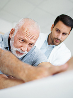 Un kinésithérapeute observe son patient qui s'étire - MACSF
