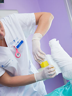 Une professionnelle de santé réalise un bandage sur le pied d'un patient - MACSF