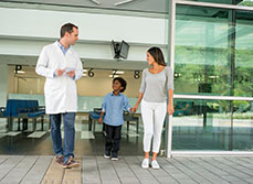 Un enfant marche à côté de sa mère et d'un médecin à l'hôpital - MACSF