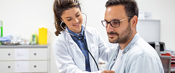 Une interne en médecine ausculte un patient au cabinet - MACSF