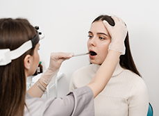 Une femme médecin examine la bouche d'une patiente - MACSF