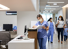 Une professionnelle de santé consulte un dossier sur le comptoir du service d'accueil de l'hopital - MACSF