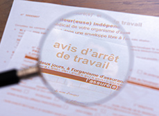 Gros plan à travers une loupe d’un formulaire officiel d’arrêt maladie de la sécurité sociale - MACSF