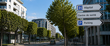 Un milieu urbain dans lequel se trouve un panneau de signalisation qui pointe vers des établissements de santé - MACSF