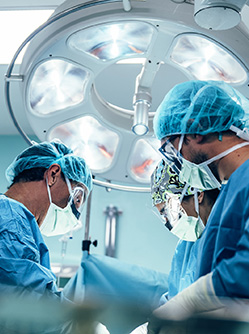 Une équipe chirurgicale vêtue de bleu penchée sur un patient - MACSF