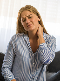 Une femme assise se tient le coup avec une expression de douleur - MACSF