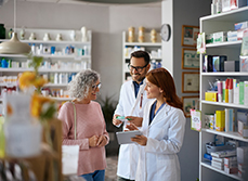 Deux pharmaciens souriants conseillent une cliente âgée - MACSF