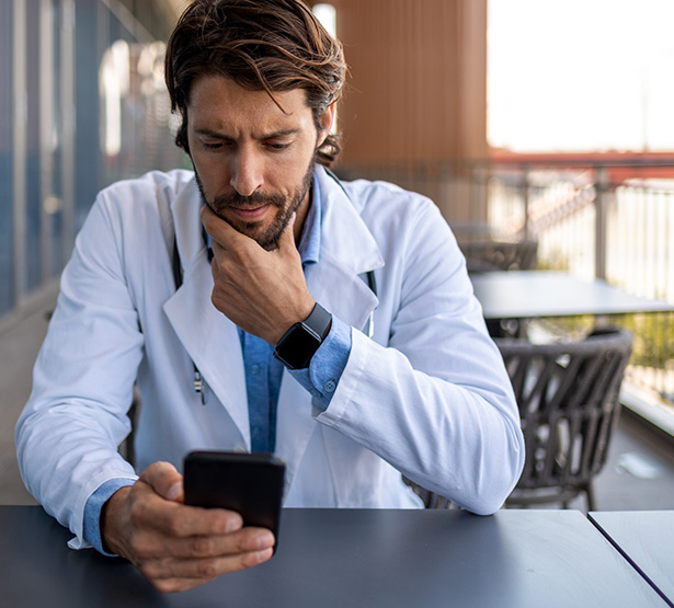 Un professionnel de santé regarde son smartphone d'un air soucieux - MACSF