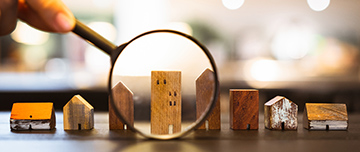 Représentation de 8 petites maisons en bois alignées et pointées par une loupe - MACSF