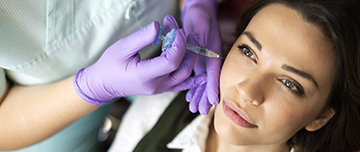 Main gantées procédant à une injection d'acide hyaluronique sur les pommettes d'une patiente - MACSF